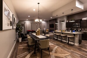 A modern kitchen with a central island, bar stools, and a dining area with a table and chairs. - Par-Tee Timers Paradise by J and Amy BL105619026 (Mesquite)