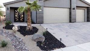 A modern two-story house with a garage, a palm tree, and a landscaped driveway. - Par-Tee Timers Paradise by J and Amy BL105619026 (Mesquite)