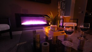 A room with a fireplace, a sofa, a coffee table with a plant, and wine glasses. - Par-Tee Timers Paradise by J and Amy BL105619026 (Mesquite)