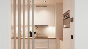 A modern kitchen with white cabinets, a marble countertop, and a wooden floor. - Georges Henri Aparthotel (Brussels)