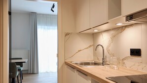 A modern kitchen with marble countertops, a stainless steel sink, and white cabinetry. - Georges Henri Aparthotel (Brussels)