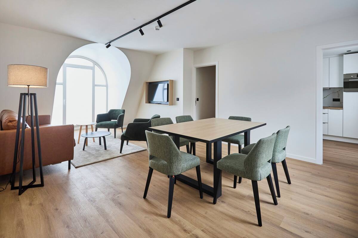 Un salon moderne comprenant un coin repas, un canapé, une lampe et un téléviseur.