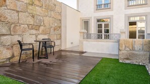 A patio with a stone wall, a wooden deck, and a small table with chairs.