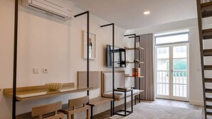 A modern living room with a glass coffee table, wooden chairs, a TV, and a balcony with a view.