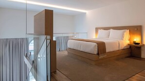 Een moderne slaapkamer met een groot bed, een nachtkastje met een lamp en een glazen hekwerk.