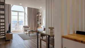Een moderne woonkamer met een groot raam, een flatscreen televisie, een bank, een salontafel en een boekenkast.
