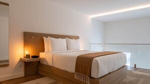 Un dormitorio moderno con una cama grande, una mesita de noche con lámpara y vistas al exterior.