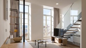 Una sala de estar moderna con una mesa de comedor de madera, un sofá, un televisor y una escalera.
