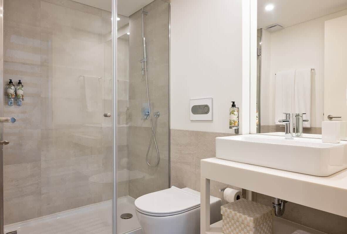 A modern bathroom with a glass-enclosed shower, a white sink, and a toilet.