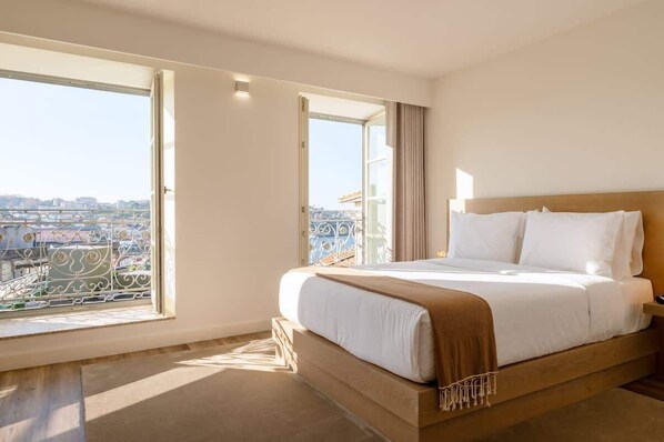 A hotel room with a large bed, a view of the city through a balcony, and a cityscape visible through the window. - Fervença Boutique Palace 6 by HostWise (Vila Nova de Gaia)