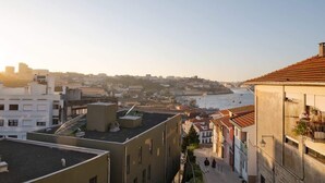Un immeuble de grande hauteur qui surplombe un paysage urbain, avec une rivière et un pont visibles au loin.