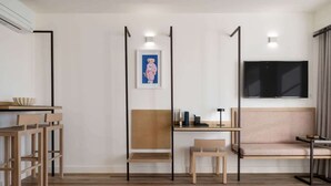 Une chambre moderne avec un plancher en bois, un bureau avec une chaise, un canapé et un téléviseur fixé au mur.