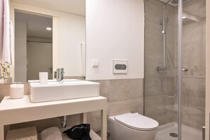 A modern bathroom with a white sink, toilet, and glass-enclosed shower. - Fervença Boutique Palace 6 by HostWise (Vila Nova de Gaia)