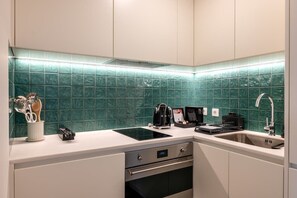 A modern kitchen with a green tiled backsplash, a built-in stove, and a sink. - Fervença Boutique Palace 6 by HostWise (Vila Nova de Gaia)