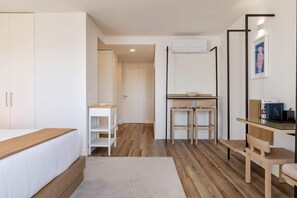 A modern room with a bed, a desk, and a chair. There is a door leading to another room. - Fervença Boutique Palace 6 by HostWise (Vila Nova de Gaia)