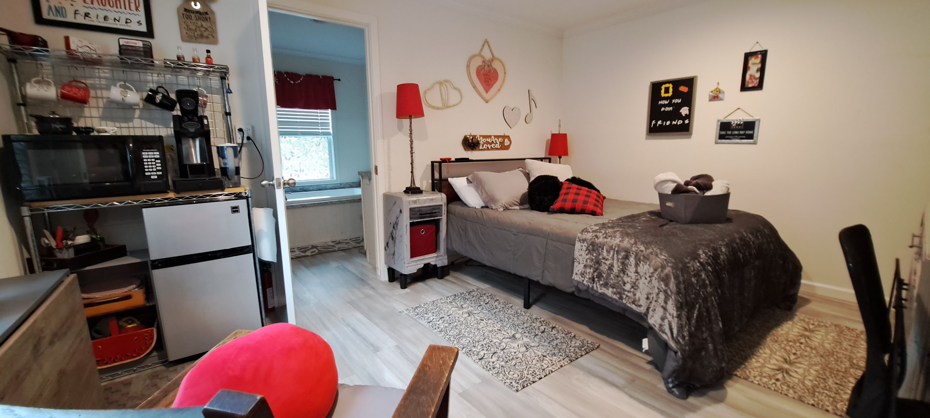 Une chambre compacte comprenant un lit, une table de chevet et un petit espace bureau avec un micro-ondes et une machine à café.