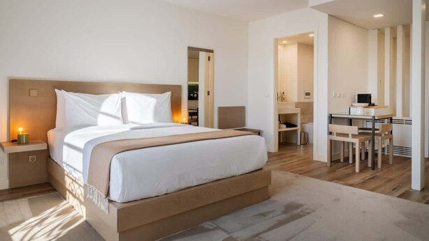 A modern hotel room with a large bed, bedside tables, a desk, and a chair.