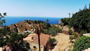 Ein Küstendorf mit Steinhäusern, Palmen und Blick auf das Meer.