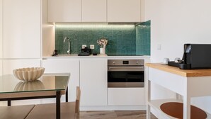 Una cocina moderna con armarios blancos, salpicadero verde y electrodomésticos de acero inoxidable.