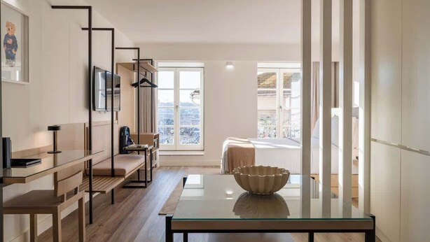 Una sala de estar moderna con una mesa de centro de vidrio, un sofá y un televisor montado en la pared.