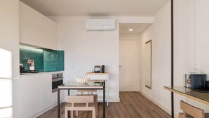 Una cocina moderna con armarios blancos, salpicadero color turquesa y una mesa de comedor de madera con sillas.