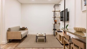 A modern living room with a sofa, a coffee table, a TV mounted on the wall, and a glass-top dining table with chairs. - Fervença Boutique Palace 4 by HostWise (Vila Nova de Gaia)