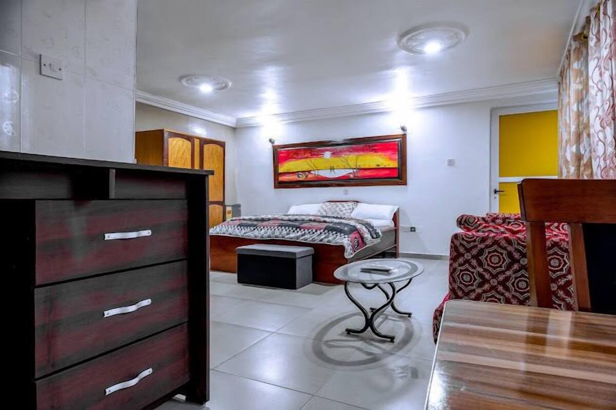 A bedroom with a bed, a bedside table, a dresser, and a painting on the wall.