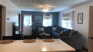 Un espacio habitable compacto con kitchenette, un sofá, una mesa de comedor y un ventilador de techo.