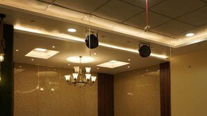 A modern lounge area with a sectional sofa, a coffee table, and a chandelier. - Maharaja Hotel and Restaurant (Ratia)