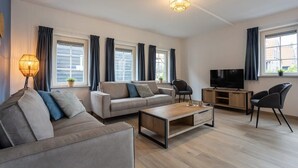 A modern living room with a sofa, coffee table, TV, and a lamp.