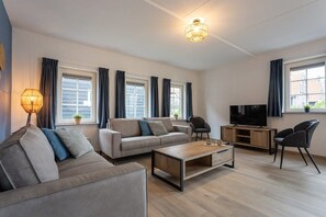 A modern living room with a sofa, coffee table, TV, and a lamp.