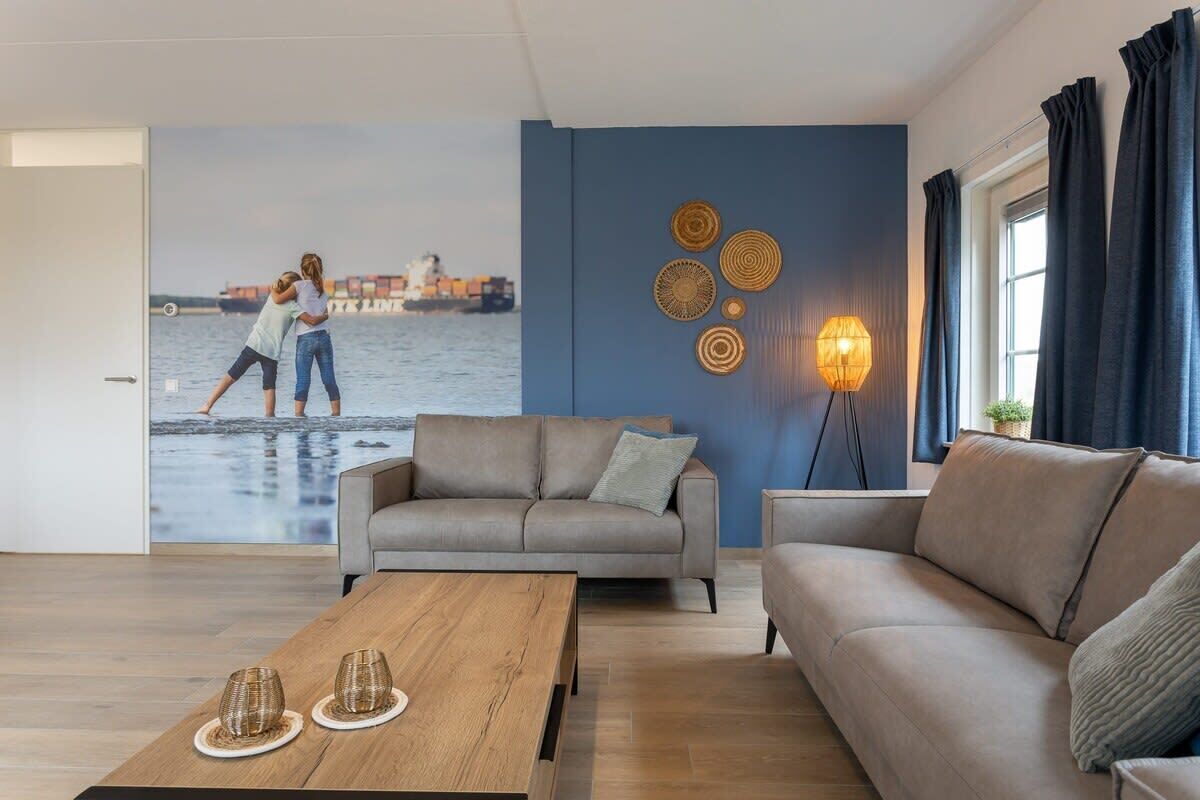 A living room with a sofa, a coffee table, and a wall mural depicting two people on a beach.
