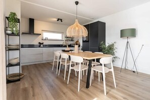 A modern kitchen with a central island, white cabinetry, and a hanging light fixture.
