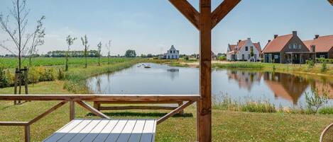 Eine Holzterrasse mit Tisch und Stühlen mit Blick auf einen ruhigen Fluss und Häuser.
