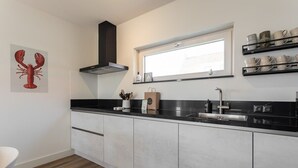Una cocina moderna con encimera negra, electrodomésticos de acero inoxidable y una ventana sobre el fregadero.