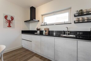Una cocina moderna con encimera negra, electrodomésticos de acero inoxidable y una ventana sobre el fregadero.