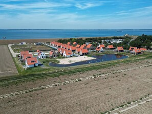 Vista aérea de un pueblo costero con casas tradicionales, un lago pequeño y campos agrícolas.