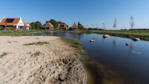 Vista a la orilla del río con casas y una playa de arena.
