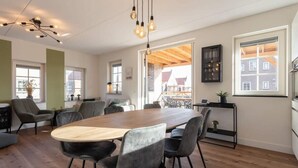 Un comedor espacioso con una mesa de madera y sillas modernas, ventanas amplias y vistas al exterior.