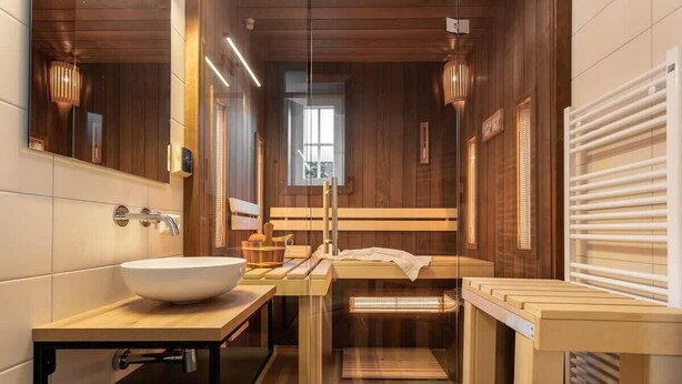 Un baño moderno con tocador de madera, un espejo grande y una sauna integrada.