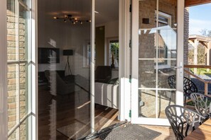 Una habitación con puerta de vidrio corredera que da a un patio con mobiliario exterior.
