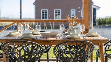 An outdoor dining area with a wooden table set for four, surrounded by black metal chairs.