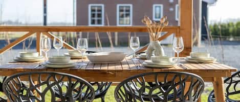 Un espace de restauration en plein air avec une table en bois prévue pour quatre personnes, entourée de chaises en métal noir.