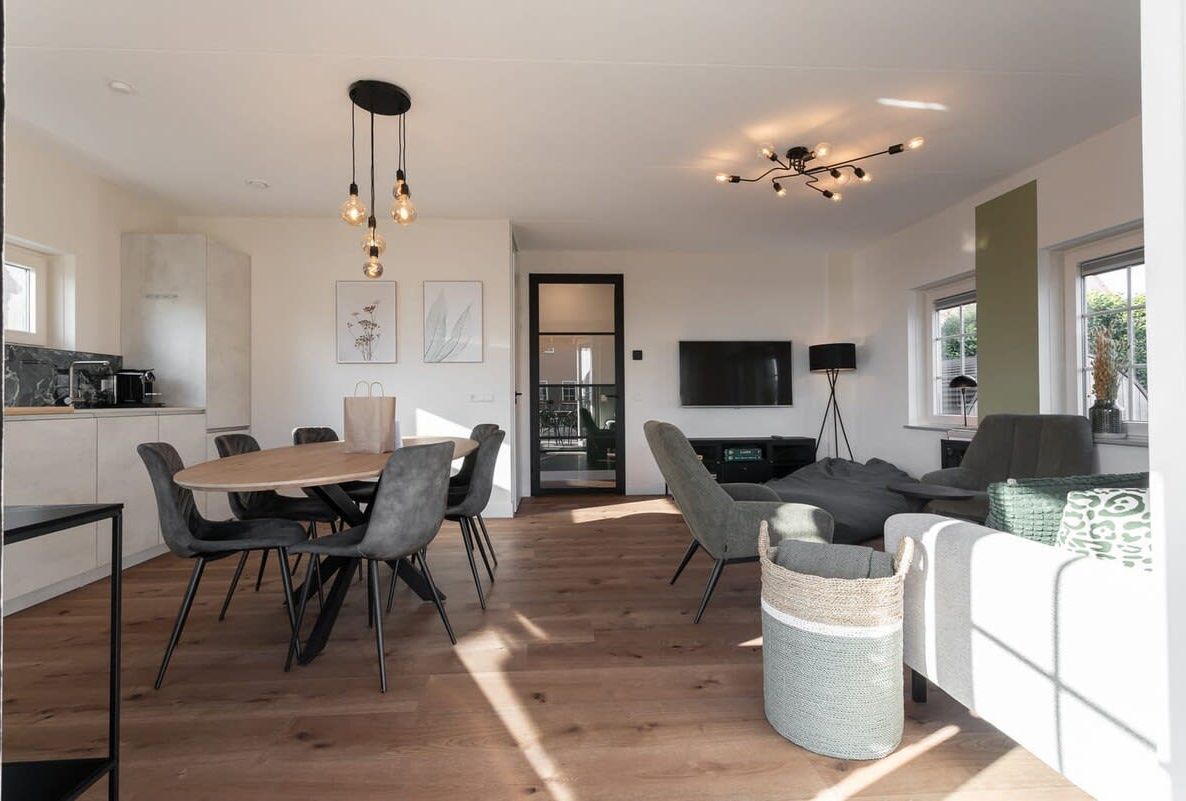 Un salon moderne avec un coin repas, un téléviseur et une cuisine en arrière-plan.