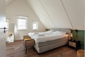 Un dormitorio con cama, mesita de noche, lámpara y ventana.