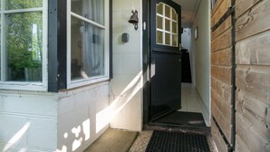 A narrow hallway with a wooden door, a window, and a doorbell.