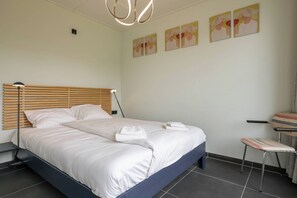 A neatly made bed with white linens and towels, a wooden headboard, and a small bedside table. - Idyllic holiday home in Aagtekerke | Kalfhoeksepad 8 (Aagtekerke)
