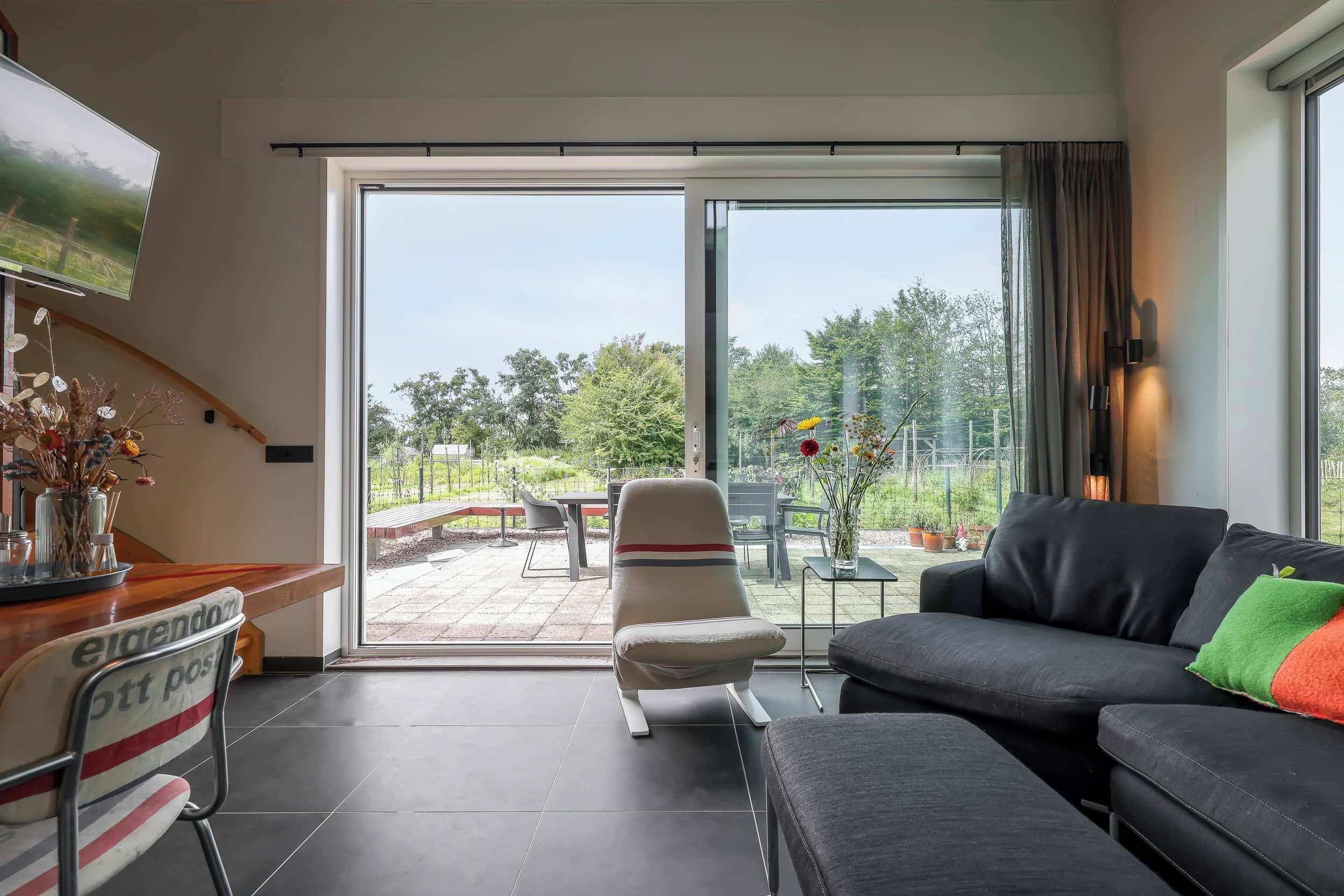A modern living room with a sofa, a chair, and a TV mounted on the wall.