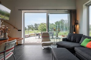 Una sala de estar moderna con un sofá, un sillón y un televisor montado en la pared.