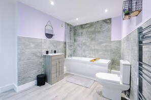 A modern bathroom with a bathtub, toilet, and vanity. - Imperial War Museum North Two-bedroom by Belvilla (Manchester)